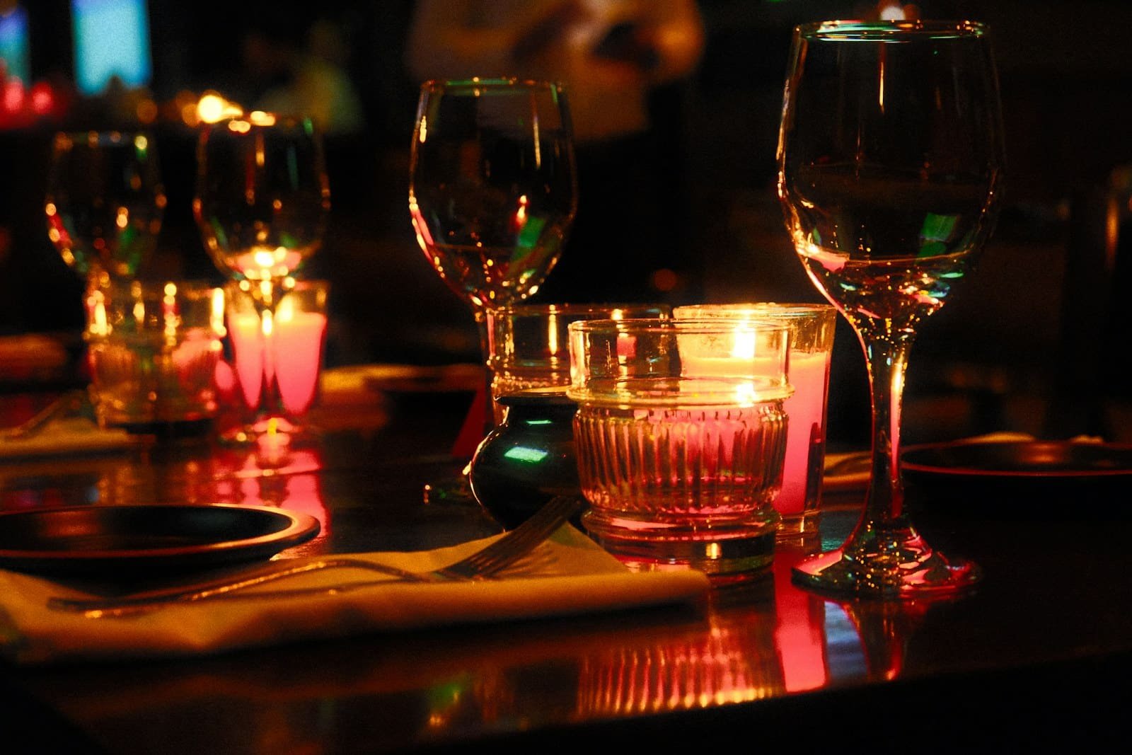 Warm candlelit restaurant table with wine glasses, illustrative romantic dinner photograph